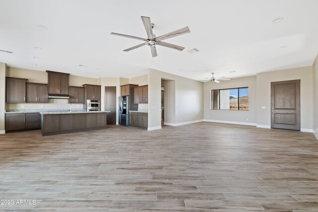 kitchen with light hardwood / wood-style flooring, stainless steel fridge, light stone counters, and ceiling fan