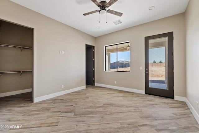 unfurnished bedroom with a walk in closet, ceiling fan, light hardwood / wood-style floors, and a closet