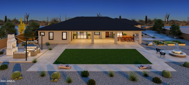 rear view of house featuring a yard, a patio area, and an outdoor living space with a fire pit