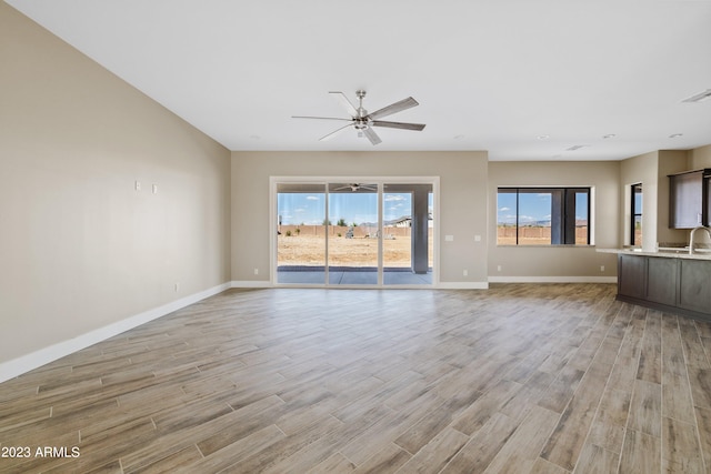 unfurnished living room with ceiling fan, sink, and light hardwood / wood-style floors