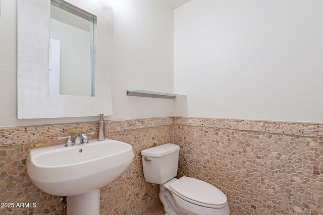 bathroom featuring toilet, sink, and tile walls