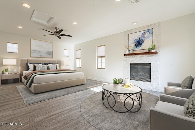 bedroom featuring hardwood / wood-style floors, a fireplace, and ceiling fan