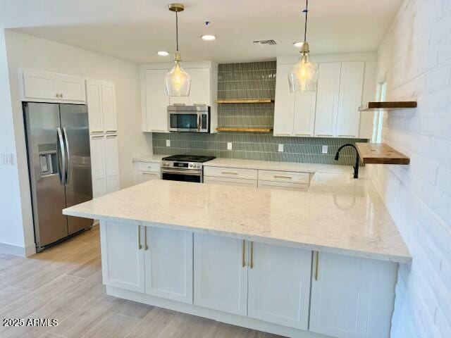 kitchen featuring open shelves, backsplash, stainless steel appliances, a peninsula, and light wood finished floors