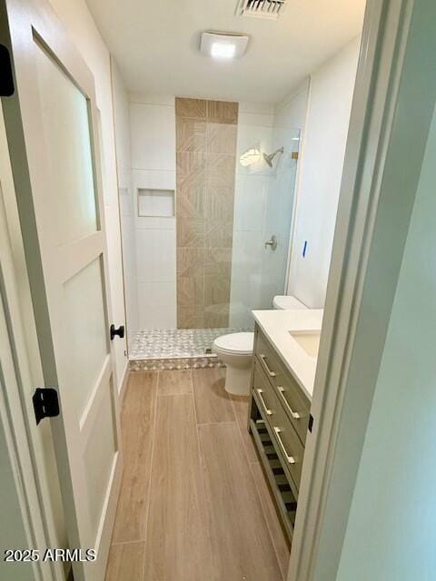 full bath with a walk in shower, toilet, vanity, and wood finish floors