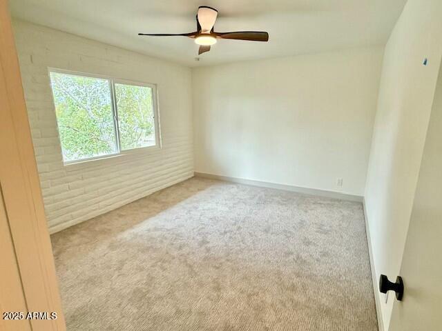 carpeted empty room featuring baseboards and ceiling fan