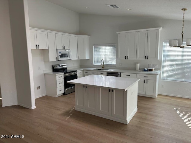 kitchen with white cabinets, sink, decorative light fixtures, appliances with stainless steel finishes, and a center island