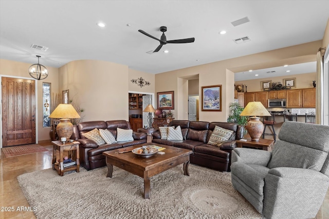 living room featuring ceiling fan with notable chandelier