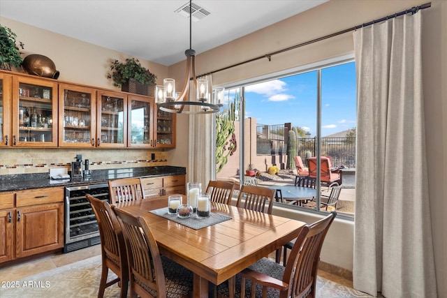 dining space featuring light tile patterned floors, beverage cooler, and an inviting chandelier