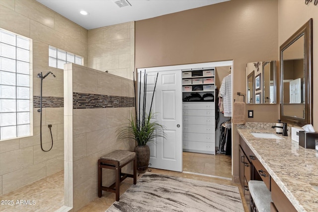 bathroom with tile patterned floors, vanity, and a tile shower