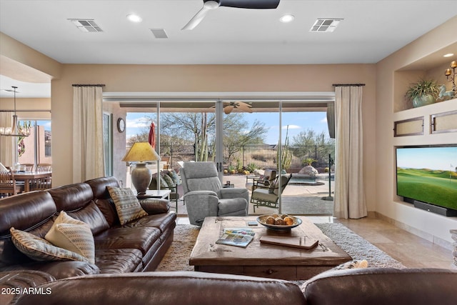 living room with ceiling fan with notable chandelier and a wealth of natural light