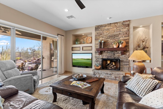 living room featuring ceiling fan, a fireplace, and built in shelves