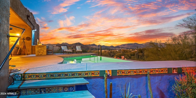 pool at dusk featuring a mountain view