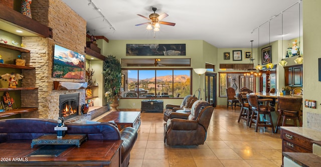 living room featuring track lighting, a fireplace, ceiling fan with notable chandelier, a mountain view, and light tile patterned flooring