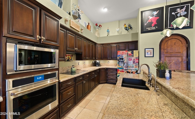 kitchen with light stone countertops, appliances with stainless steel finishes, sink, decorative light fixtures, and light tile patterned flooring