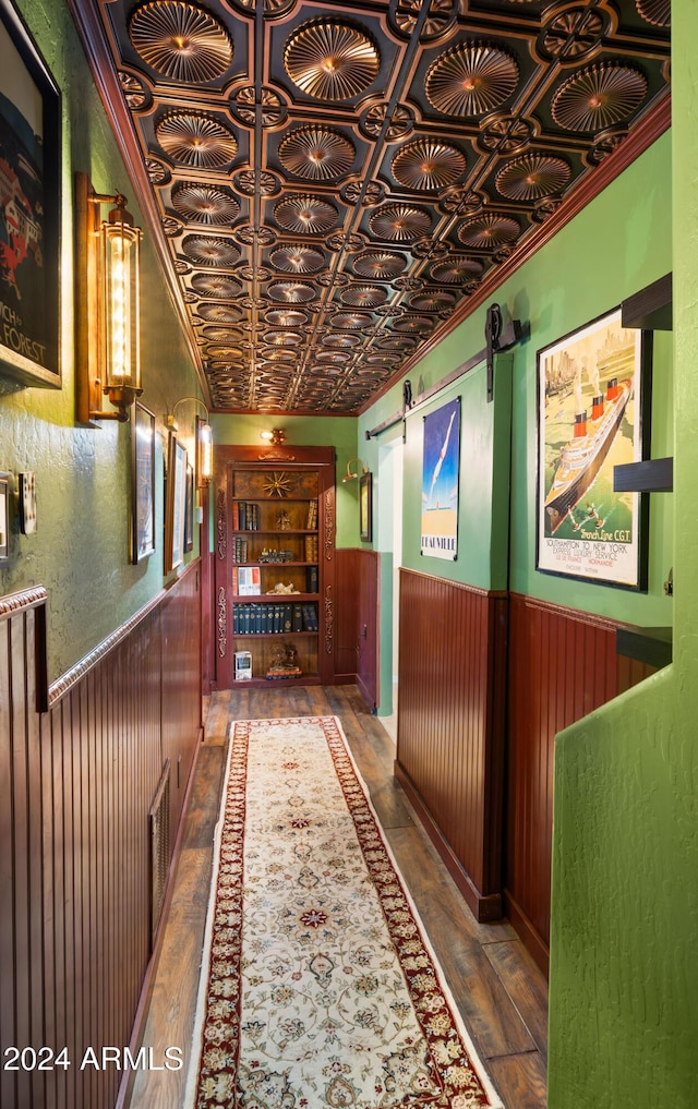 hallway with hardwood / wood-style floors, a barn door, and wooden walls