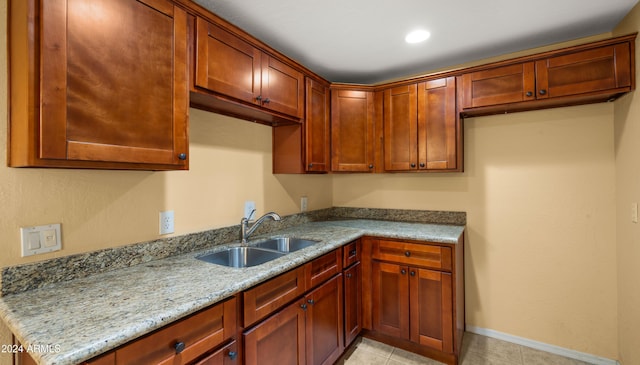 kitchen with light stone counters, light tile patterned floors, and sink