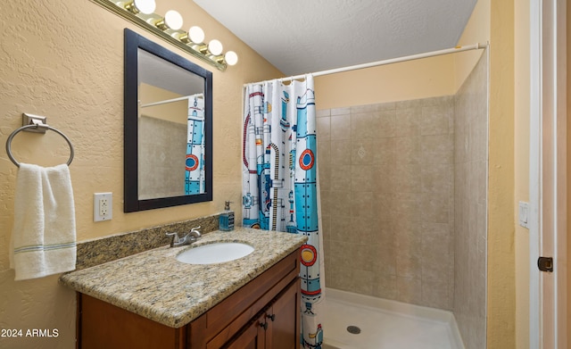 bathroom with curtained shower, vanity, and a textured ceiling