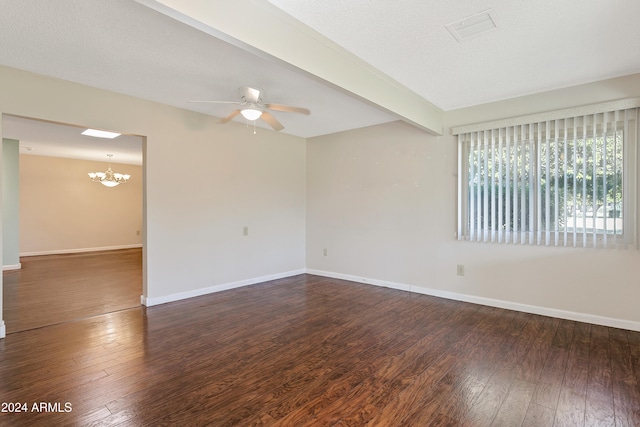 empty room featuring ceiling fan with notable chandelier, a textured ceiling, dark hardwood / wood-style flooring, and beamed ceiling