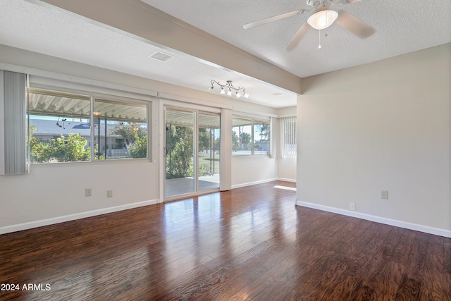 unfurnished room with dark wood-type flooring, plenty of natural light, a textured ceiling, and ceiling fan