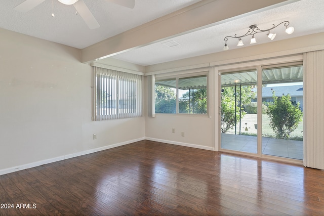 unfurnished room with ceiling fan, plenty of natural light, a textured ceiling, and dark wood-type flooring