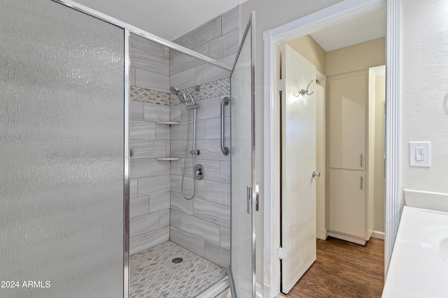 bathroom with a shower with shower door and hardwood / wood-style floors