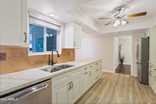 kitchen with light wood-type flooring, stainless steel appliances, light stone counters, and sink