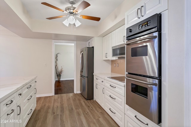 kitchen with white cabinetry, ceiling fan, appliances with stainless steel finishes, light wood-type flooring, and light stone countertops