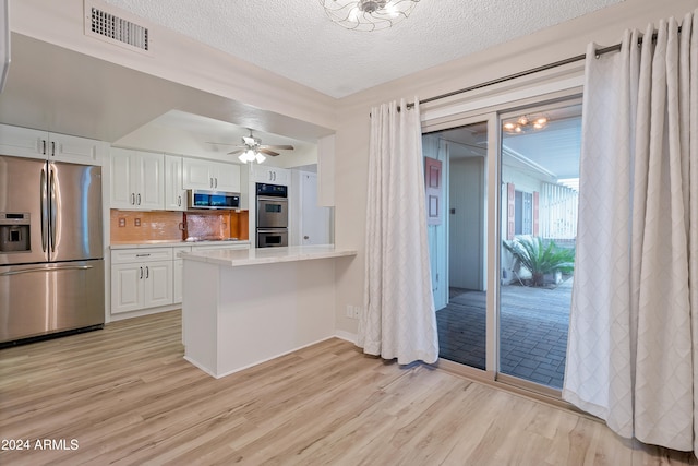 kitchen featuring white cabinets, stainless steel appliances, light hardwood / wood-style floors, backsplash, and kitchen peninsula