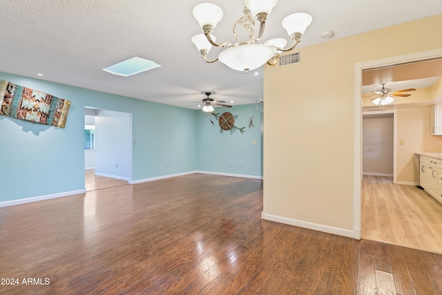 spare room featuring a skylight, ceiling fan with notable chandelier, a textured ceiling, and light hardwood / wood-style floors