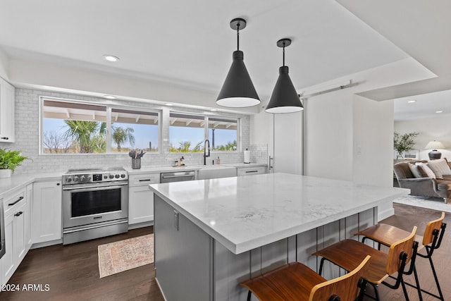 kitchen featuring dark wood-type flooring, tasteful backsplash, pendant lighting, and appliances with stainless steel finishes