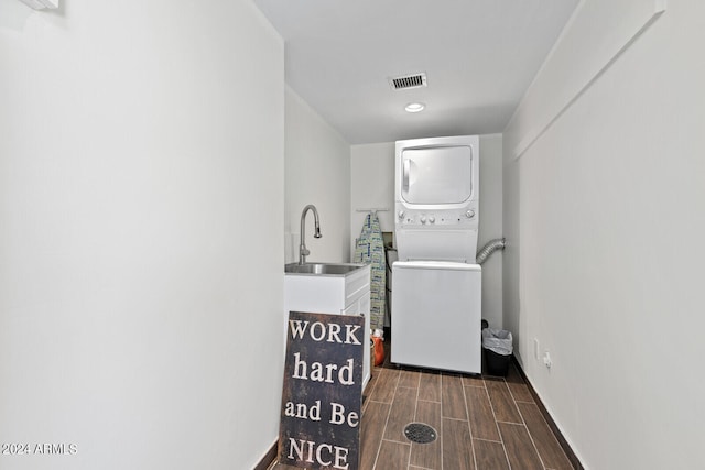 laundry area with sink, stacked washing maching and dryer, and hardwood / wood-style floors