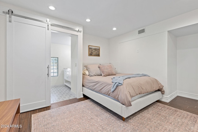 tiled bedroom featuring a barn door and ensuite bathroom