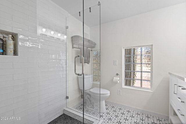 bathroom featuring a healthy amount of sunlight, toilet, tile floors, and a shower with door