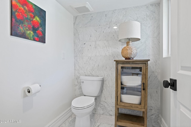 bathroom with tile flooring, tile walls, and toilet