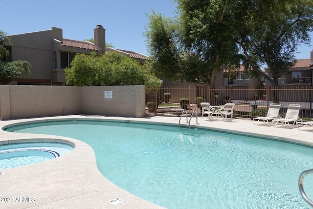 pool with a patio, a hot tub, and fence