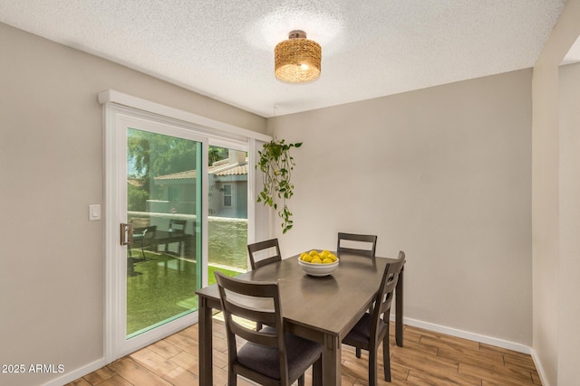 dining room featuring a textured ceiling, baseboards, and wood finished floors