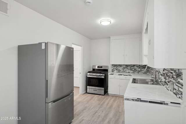541 W Vernon Ave, Phoenix, AZ 85003 - kitchen with stainless steel appliances, decorative backsplash, light countertops, light wood finished floors, and white cabinetry