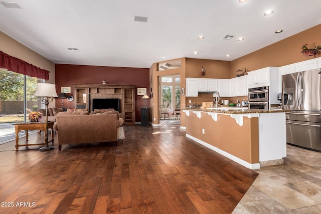 kitchen with stone counters, appliances with stainless steel finishes, a healthy amount of sunlight, and white cabinetry