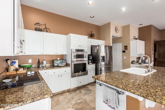 kitchen with white cabinets, appliances with stainless steel finishes, sink, and dark stone counters