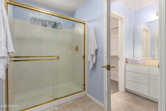 bathroom featuring tile patterned floors, a shower with door, and vanity