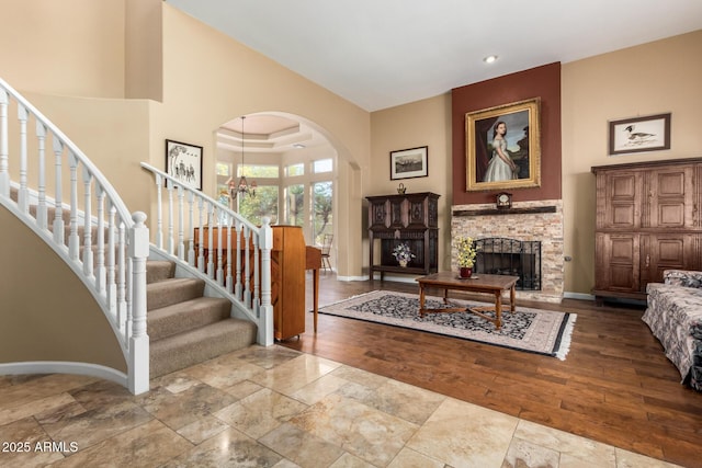 living room featuring a towering ceiling, a stone fireplace, and a notable chandelier