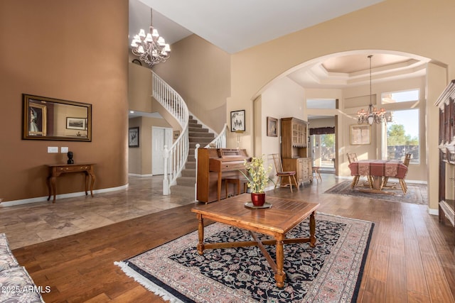 living room with a chandelier, a raised ceiling, a towering ceiling, and dark hardwood / wood-style flooring