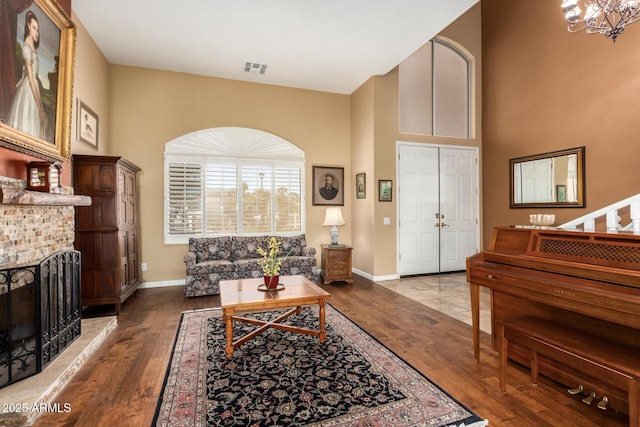 living room featuring a brick fireplace, hardwood / wood-style flooring, and an inviting chandelier