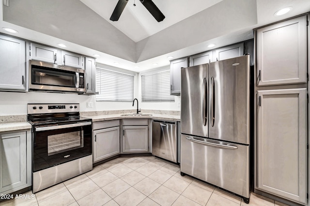 kitchen featuring lofted ceiling, stainless steel appliances, sink, light tile patterned flooring, and gray cabinetry