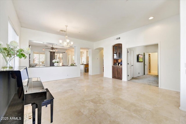 living area with visible vents, arched walkways, and ceiling fan with notable chandelier