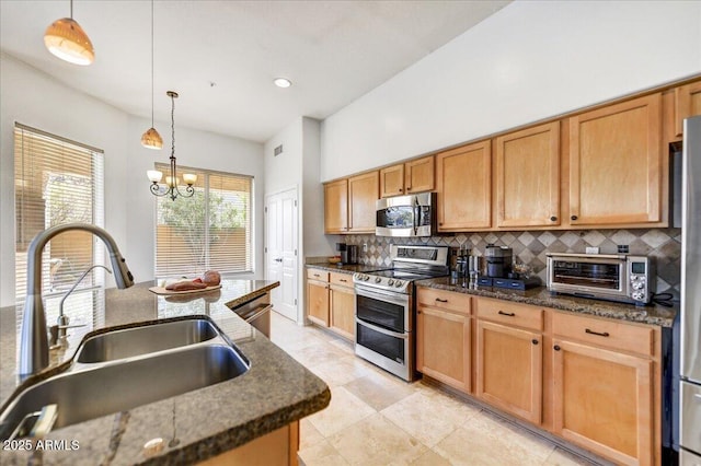 kitchen featuring pendant lighting, a toaster, backsplash, appliances with stainless steel finishes, and a sink