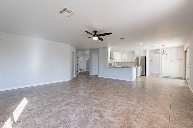 unfurnished living room featuring ceiling fan with notable chandelier and sink