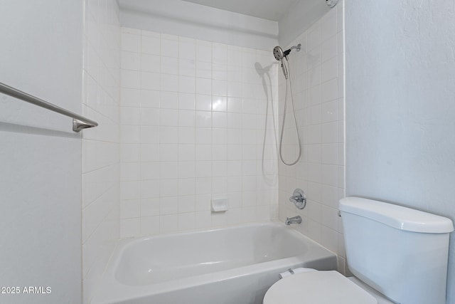 bathroom featuring tiled shower / bath combo and toilet