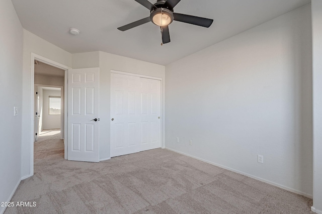 unfurnished bedroom featuring ceiling fan, light colored carpet, and a closet