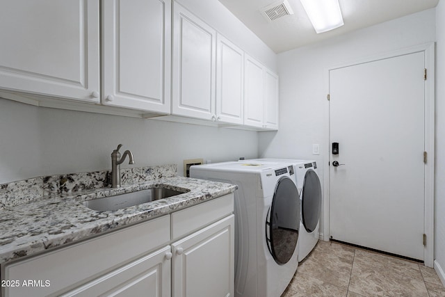 clothes washing area featuring cabinets, sink, and washing machine and clothes dryer